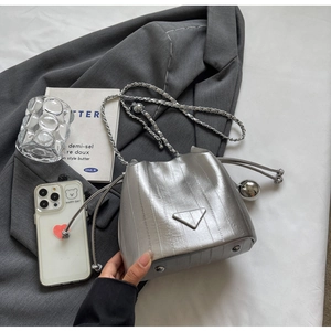 Detail of silver bucket bag featuring vertical texture and iconic triangular metal logo