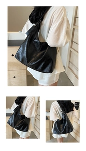 Detail of black glossy crinkled leather hobo bag with wide shoulder strap and spacious design