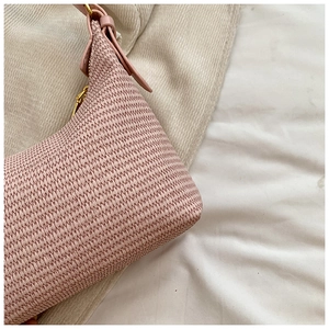 Détail de la texture tressée rose du sac à bandoulière avec fermetures en métal doré