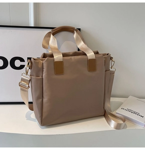 Detail of khaki nylon tote bag showing side pocket, gold hardware and handles