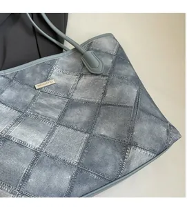 Detail of grey denim print tote bag featuring square stitching and metal logo plaque