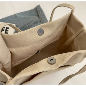Detail view of the canvas tote bag interior with magnetic buckle and inner zipper pocket