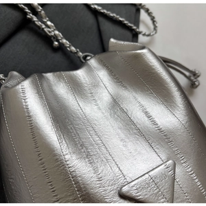 Detail showing metallic silver pleated texture and triangle metal logo on the chain bag