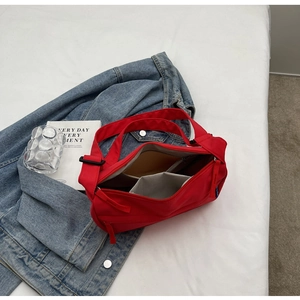Detail view of red nylon dumpling bag with top zipper and spacious grey interior lining