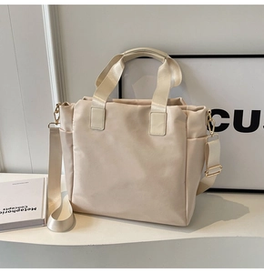 Detail view of beige tote bag side pocket with adjustable strap and metallic hardware