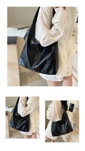Macro detail of large black tote bag featuring crinkled texture and vertical stitching
