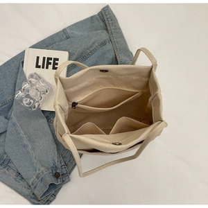 Top view of canvas tote interior showing zip pocket, compartments and magnetic closure