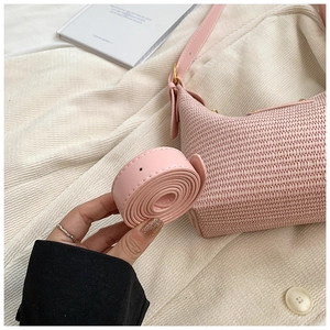Gros plan du sac hobo en paille tissée rose avec bandoulière réglable