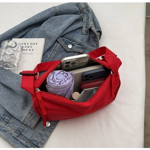 Detail showing the large interior capacity of this red crossbody bag with daily essentials