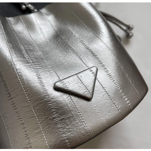 Macro shot of silver pleated texture and triangular logo on a designer bucket bag