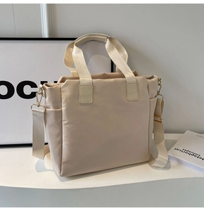 Detail of beige quilted nylon tote bag with adjustable strap and smooth side pockets