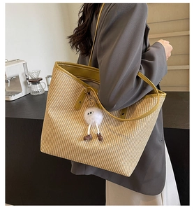 Gros plan sur un grand sac cabas en paille avec charm peluche et bandoulière