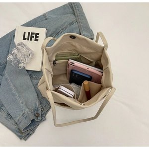 Top view of large beige canvas bucket bag interior with organized compartments and laptop