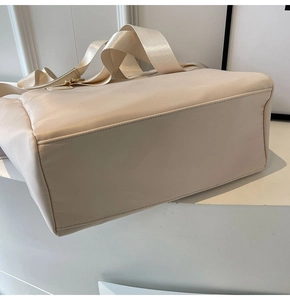 Detail view of the beige nylon tote bag showing wide straps and golden metal hardware