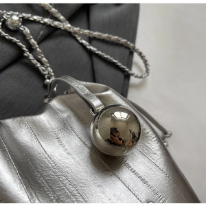 Detail of silver textured crossbody bag with metallic sphere clasp and chain strap