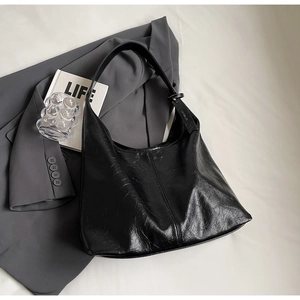 Detail of large black shoulder bag featuring textured faux leather and a minimal tag