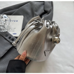 Detail of silver bucket bag with metal triangle logo and sphere charm on grey suit jacket