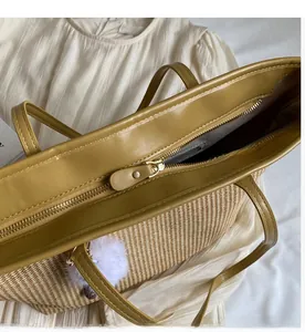 Détail d'un sac cabas en paille avec fermeture éclair métallique et bordure jaune moutarde