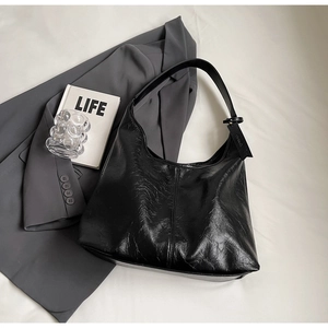 Close-up of black pleated faux leather hobo bag on a grey blazer with stylish texture