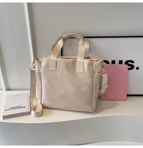 Detail view of large beige tote bag with detachable wide shoulder strap and gold hardware