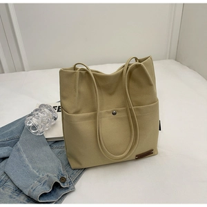 Detailed close-up of khaki canvas tote bag featuring metal magnetic snap and leather tag