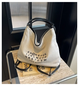 Detailed close-up of herringbone canvas texture and black lettering on large tote bag