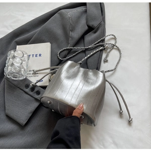 Macro detail of silver metallic bucket bag with drawstring closure and metal feet