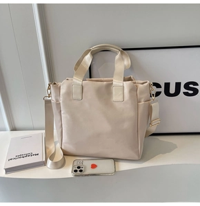 Detail of cream tote bag with nylon texture, side pocket, and adjustable strap