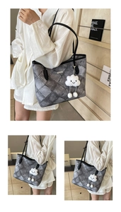 Detail of grey quilted tote bag with a white plush cloud charm and metal logo accent
