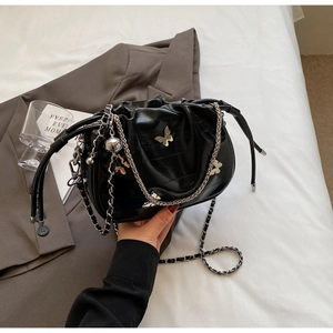 Détail du sac seau noir avec pendentif papillon et bandoulière chaîne argentée