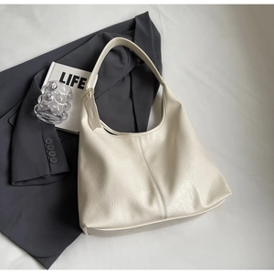 Close-up of the wrinkled leather texture on a cream white large tote shoulder bag