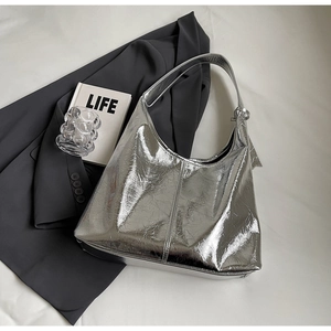 Detail of silver metallic textured fabric and shoulder strap on a spacious shoulder bag