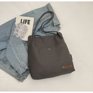 Detail of dark gray canvas tote bag with magnetic snap and leather logo patch