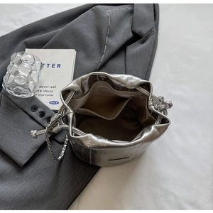 Macro shot of silver bucket bag interior showing zipper pocket and metallic chain strap
