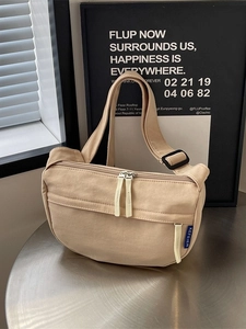 Minimalist beige canvas crossbody dumpling bag with adjustable strap and dual zippers