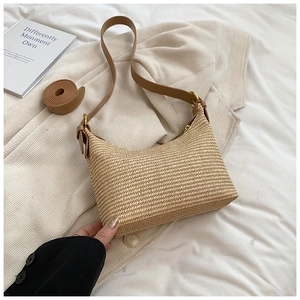 Détail d'un sac à bandoulière en paille avec lanières en cuir et garnitures en métal doré