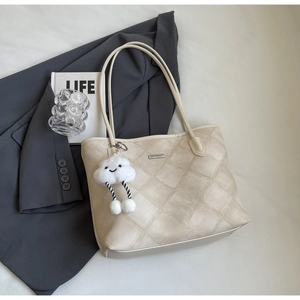 Detail of beige quilted tote bag with soft texture and cute white cloud charm