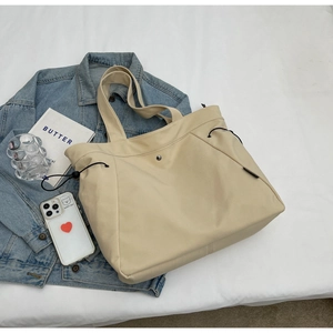 Top view of beige nylon tote bag with adjustable side drawstrings and magnetic closure