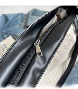 Detailed close-up of smooth silver metal zipper and black trim on canvas tote bag