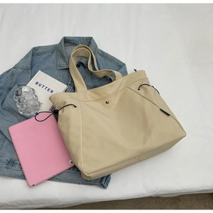Detail shot of beige nylon tote bag with drawstring side and metal button closure