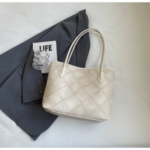 Close-up of a cream beige quilted tote bag featuring a textured rhombus stitched pattern