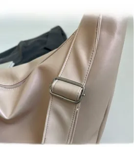 Detailed close-up of adjustable strap with shiny silver hardware on a soft pink handbag