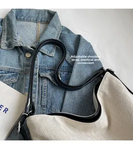 Detail of canvas tote bag with adjustable leather strap resting on a denim jacket