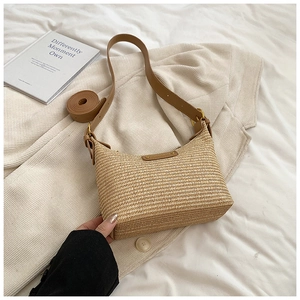 Détail du sac hobo en paille tissée avec bandoulière en cuir marron et boucle dorée sur tissu