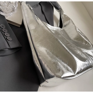 Detail of silver metallic tote bag featuring pleated texture and wide shoulder strap
