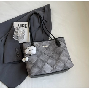 Close-up of gray quilted tote bag with denim texture and white cloud plush charm detail