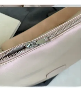 Close-up of smooth silver metal zipper on a premium pearlescent pink shoulder bag