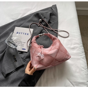 Pink quilted hobo bag with drawstring detail and leather chain strap in a lifestyle setting