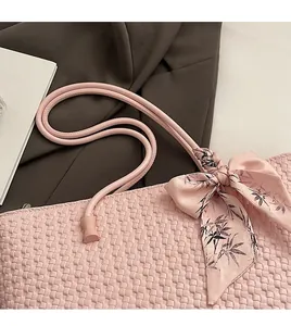 Pink woven tote bag detail with decorative floral silk scarf and round shoulder strap