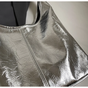 Close-up of metallic silver leather texture with wrinkled finish and detailed stitching